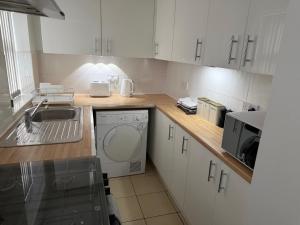 a white kitchen with a sink and a dishwasher at GS Maisons Hideaway in Sheffield