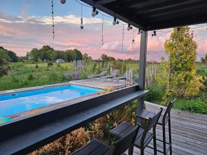 a patio with a pool and chairs on a deck at Vaitų Riešutynė - Small shipping container house in Antanava