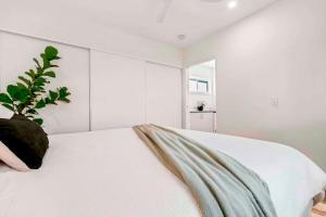 a white bedroom with a potted plant sitting on a bed at Private Modern Bungalow - Separate Entry in Brisbane