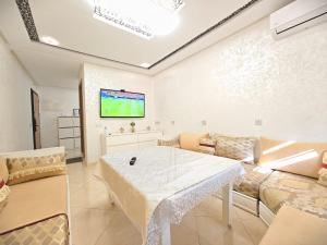 a living room with a table and a tv at Ryad el houda in Agadir