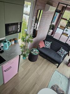 a living room with a black couch in a kitchen at Vaitų Riešutynė - Small shipping container house in Antanava