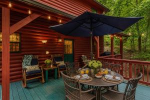 a wooden deck with a table and an umbrella at Quiet mornings and golden hour views welcome to our woodland sanctuary Deer Watch Retreat in Ellijay