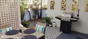 an outdoor patio with two tables and a grill at The Boathouse a 3 Bedroom Holiday Home in Narooma
