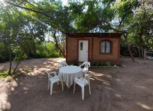 a table and chairs in front of a small cabin at La Quebrada del Molle in San Marcos Sierras