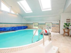 a swimming pool with blue water in a room with skylights at 4 star holiday home in Ørsted-By Traum in Ørsted