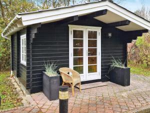 a black house with a chair in front of it at 4 star holiday home in Hemmet in Hemmet +28 photos