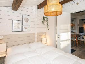 a white bedroom with a bed and a chandelier at 4 star holiday home in Hemmet in Hemmet