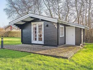 a small black shed with a white door in the grass at 4 star holiday home in Hemmet in Hemmet