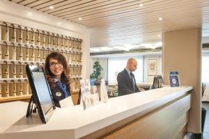 a woman and a man standing in front of a bar at Best Western Hotel Residence Italia in Quartu SantʼElena