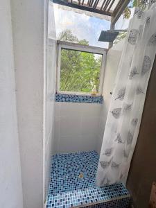 a bathroom with a shower with a window and a blue tile floor at Intimunay Shala Yoga Center in Las Núñez