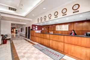 a woman sits at the reception desk in a lobby at Ramada Plaza by Wyndham Atlanta Airport in Atlanta