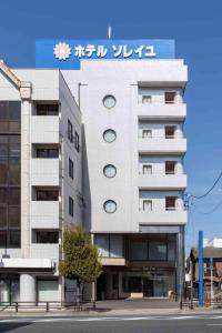 a white building with a sign on top of it at Hotel Soleil in Iwaki