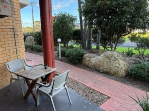 a wooden table and two chairs next to a building at Ulladulla Harbour Motel in Ulladulla