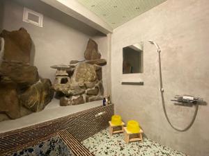 a bathroom with a shower and a rock wall at 姫路城下町 巡 in Himeji