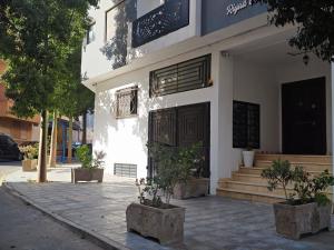 a white building with a door and some trees at Ryad el houda in Agadir