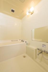 a white bathroom with a tub and a mirror at Hotel Soleil in Iwaki