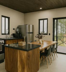 a kitchen with a large wooden table and a refrigerator at La Cima Escondida Bijagua Rio Celeste 20 Min in Upala