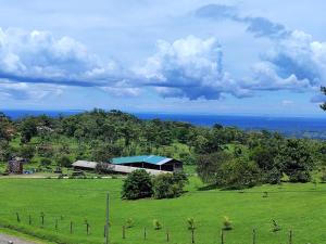 a green field with a building in the distance at La Cima Escondida Bijagua Rio Celeste 20 Min in Upala +14 photos