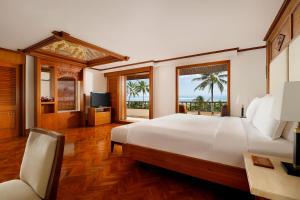 a bedroom with a large white bed and windows at Nusa Dua Beach Hotel and Spa - Handwritten Collection in Nusa Dua