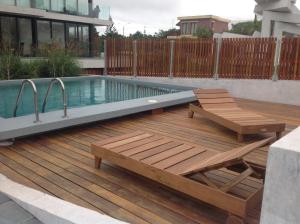 una terraza de madera con piscina, banco y mesa en Apartamento Rambla 24, en Punta del Este