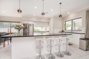 a kitchen with white cabinets and a large island with stools at Charming 3-Bed Getaway with Pool & Garden Oasis in Lyons