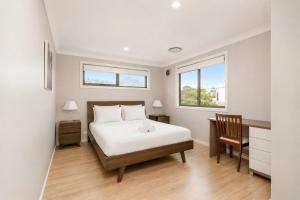a bedroom with a bed and a desk and two windows at Charming 3-Bed Getaway with Pool & Garden Oasis in Lyons +10 photos