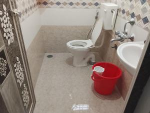 a bathroom with a toilet and a sink and a bucket at Pemmis living space in Bangalore