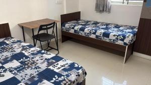a room with two beds and a table and a chair at Pemmis living space in Bangalore