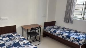 a room with two beds and a table and a desk at Pemmis living space in Bangalore