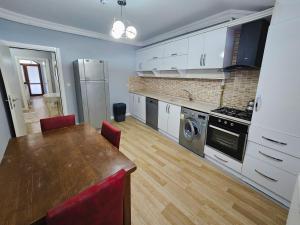 a kitchen with white cabinets and a table with red chairs at yomra apart otel in Yomra