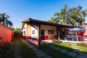 a house with a patio and a table and an umbrella at Sinuca, churrasqueira e fogueira a 300 metros do mar in Itanhaém