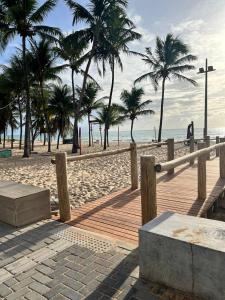 a wooden boardwalk on a beach with palm trees at Flat 4 Mares - Refugio a dois - Com piscina e estacionamento em Intermares in Cabedelo