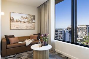a living room with a couch and a large window at Adina Chermside Brisbane in Brisbane
