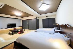 a bedroom with two beds and a flat screen tv at Yutorelo Yamaga in Yamaga