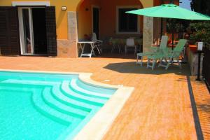 a swimming pool with an umbrella and a table and chairs at Happy Holiday Villa - Pool & Garden in Syracuse