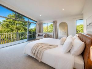 a white bedroom with a large bed and large windows at Oneroa Vines and Views- Stay Waiheke in Blackpool