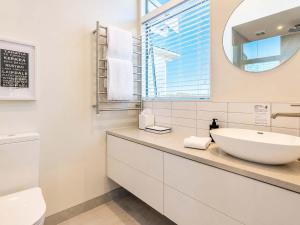 a white bathroom with a sink and a mirror at Oneroa Vines and Views- Stay Waiheke in Blackpool +20 photos