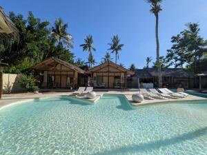 a swimming pool with lounge chairs and palm trees at Meno Lagoon Bungalows in Gili Meno