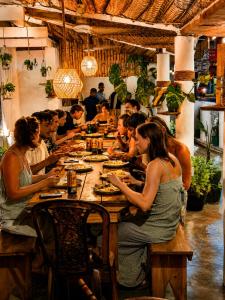a group of people sitting at a long table in a restaurant at Wave Hunters Arugam Bay in Arugam Bay