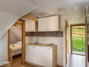 a kitchen with white cabinets and a bed in a room at Nature Escape with Pool & Garden Views in Karlovac