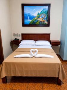 a bed with two white towels on top of it at Hotel Milenio in Guayaquil