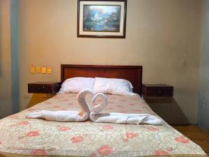 a bed with two towels in the shape of a heart at Hotel Milenio in Guayaquil