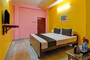 a bedroom with a bed with yellow and pink walls at Hotel O by OYO Red Rose Near Noapara Metro Station in Kolkata +22 photos