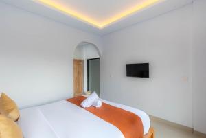 a bedroom with a white bed and a tv at Kubu YN Bali in Jimbaran