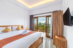 a bedroom with a bed and a television and a balcony at Kubu YN Bali in Jimbaran