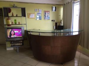 a living room with a tv and a glass table at Hotel Santa Inez in Nazaré da Mata
