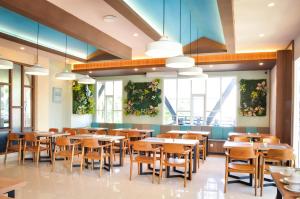 a dining room with tables and chairs and plants on the walls at Hexton Hotel Lampung in Tanjungkarang