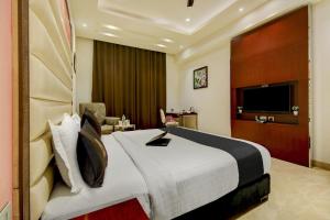 a hotel room with a large bed and a television at Super Townhouse Oak Hotel C Pearls in New Delhi