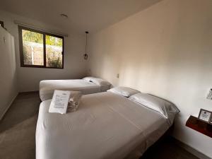 two beds in a small room with a window at Tropical Garden Suites steps from the Lagoon in Bacalar
