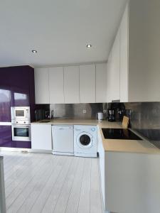 a kitchen with white cabinets and a washing machine at Beach Hub in São Martinho do Porto